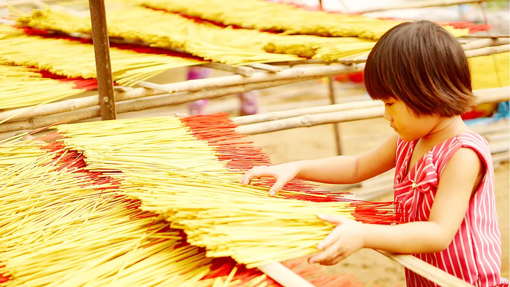 Một cô bé 9 tuổi đã biết phụ giúp gia đình phơi nhang tại làng nhang Lê Minh Xuân