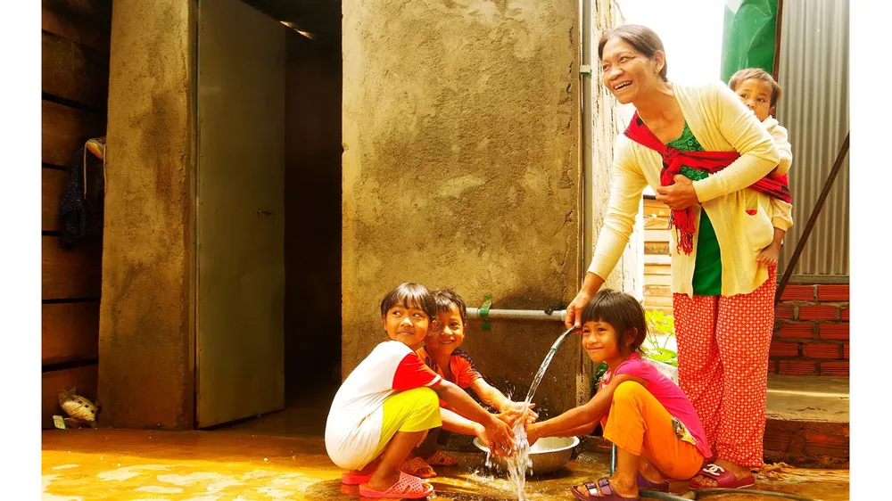 Bà H’Nhêr (dân tộc M’Rông) và con cháu bên dòng nước sạch  được kéo về tận nhà