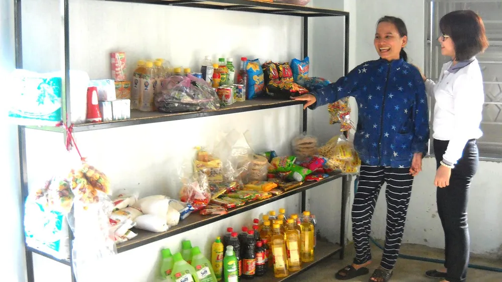 Chị Diệu trước kệ bán hàng do chị Nhung (bên phải) tặng