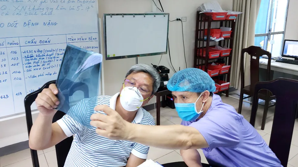 Thứ trưởng Bộ Y tế Nguyễn Trường Sơn (trái) trực tiếp theo dõi  tình hình sức khỏe bệnh nhân Covid-19 tại Bệnh viện Phổi Đà Nẵng. Ảnh: NGUYỄN CƯỜNG