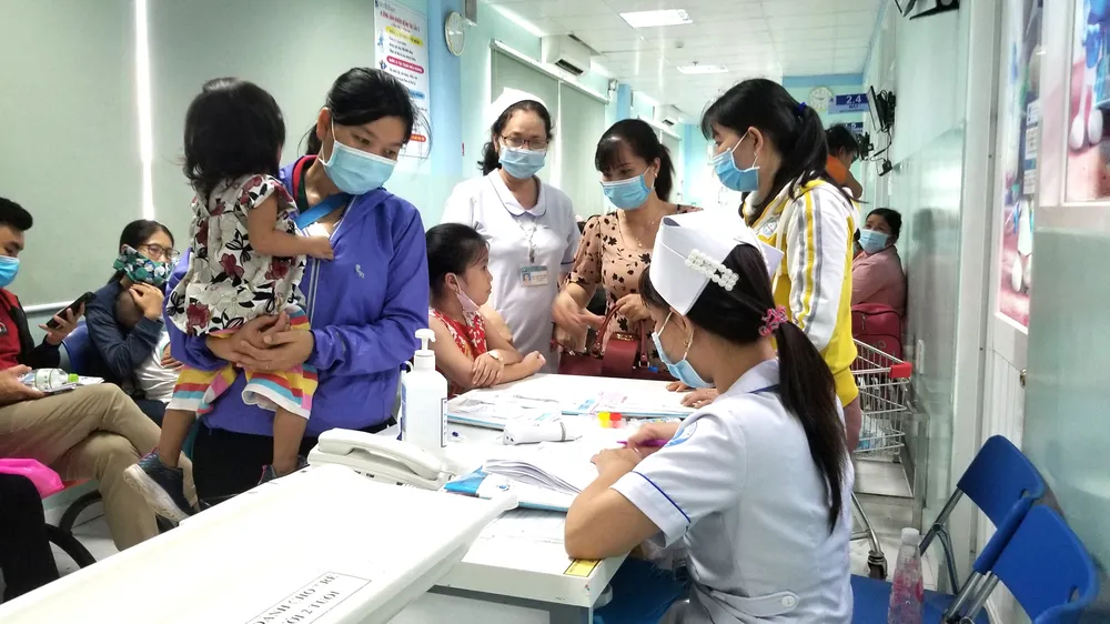 Phụ huynh bồng bế trẻ chờ thăm khám  tại Khoa Hô hấp Bệnh viện Nhi đồng 1 sáng 27-10