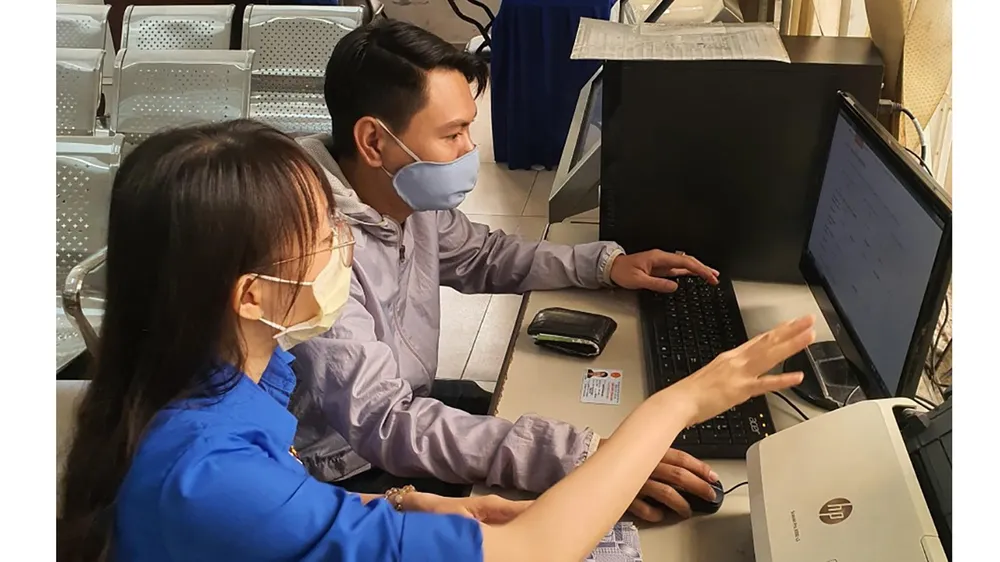 Công chức UBND quận Bình Thạnh hướng dẫn người dân  thực hiện đăng ký hồ sơ qua mạng. Ảnh: Thái Phương