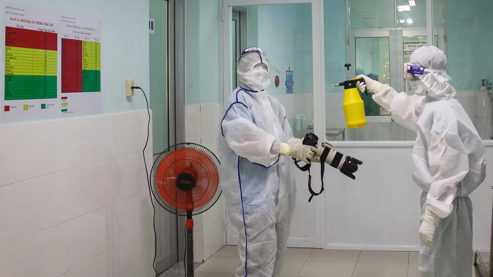 Phóng viên  Báo SGGP thực hiện nghiêm túc và đầy đủ việc khử trùng để vào Bệnh viện Huyện Củ Chi tác nghiệp. Ảnh: DŨNG PHƯƠNG