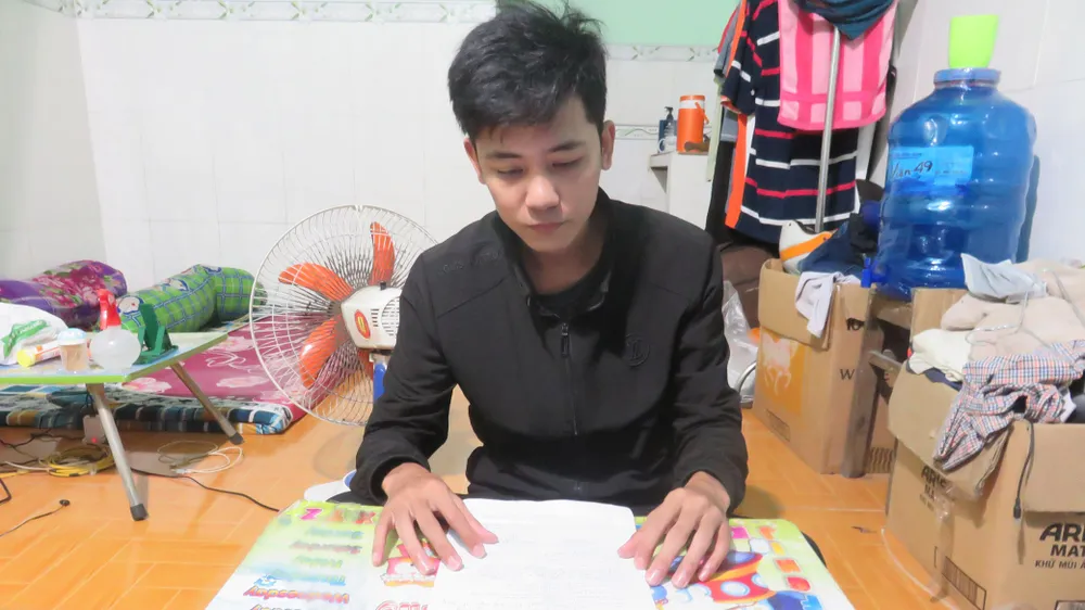 Anh Lê Văn Nhí xem lại mẫu đơn đề nghị hỗ trợ tiền nhà trọ  do công ty cung cấp. Ảnh: MINH NGHĨA