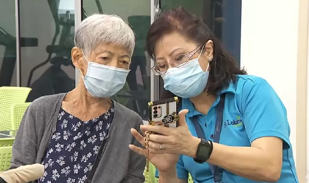 Tình nguyện viên hướng dẫn cụ Pauline Tong sử dụng các ứng dụng chăm sóc sức khỏe