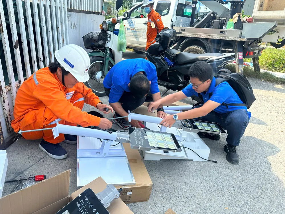 Anh Nguyễn Hoàng Thắng (bên phải) cùng đồng nghiệp thực hiện công trình thanh niên lắp đặt đèn năng lượng mặt trời cho các tuyến hẻm
