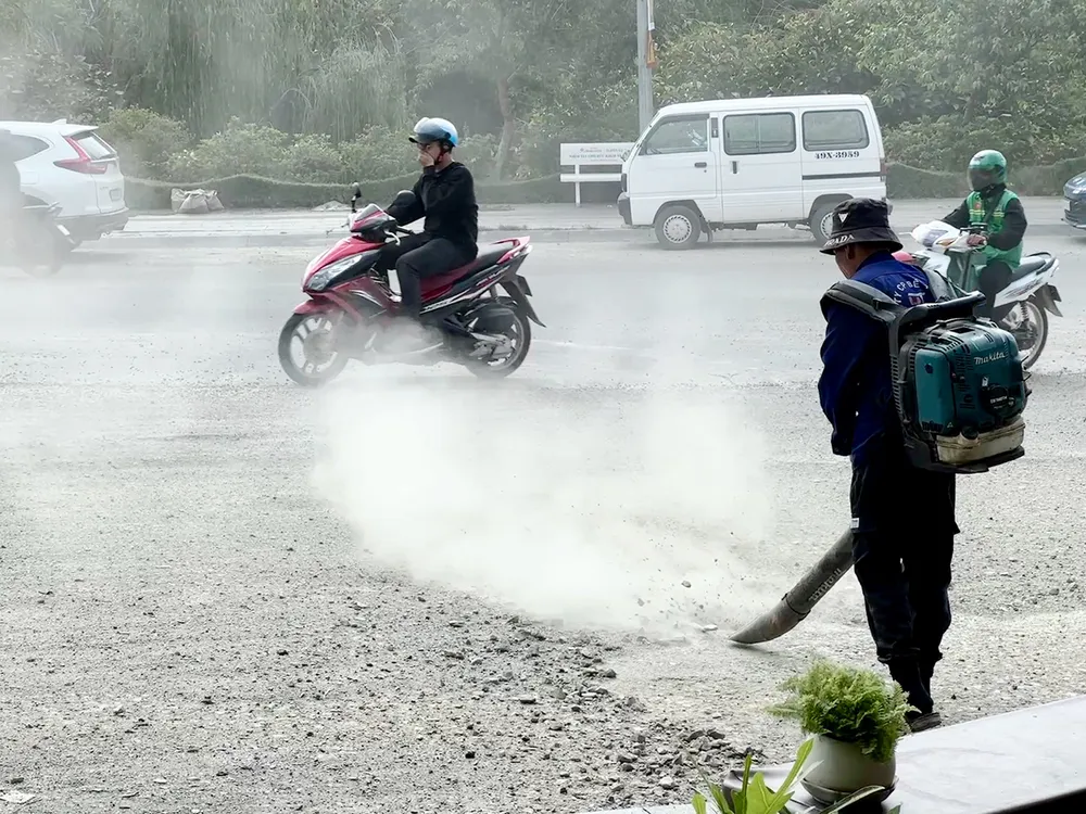 Công nhân sử dụng máy thổi công suất lớn thổi bụi vào người đi đường