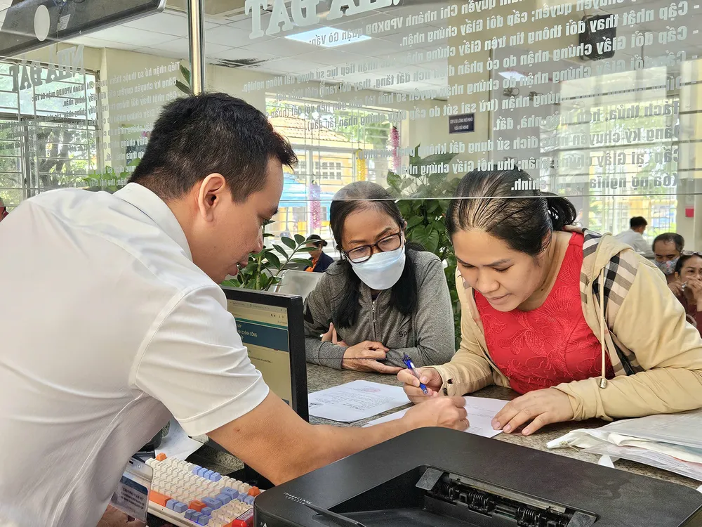 Ông Trương Văn Sự, thành viên tổ địa bàn tại Trung tâm Phục vụ hành chính công phường Gò Vấp, TPHCM hướng dẫn người dân thực hiện thủ tục hành chính. Ảnh: NGÔ BÌNH