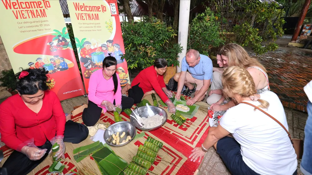 Du khách Ba Lan trải nghiệm gói bánh tét tại Đồng Tháp, chiều 5-2. Ảnh: BẢO THU