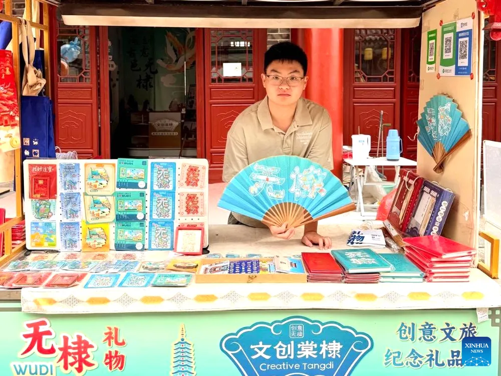 Lý Trạch Di bán các sản phẩm do chính anh thiết kế trước cửa hàng văn hóa và sáng tạo của mình tại huyện Vũ Đế. Ảnh: THX