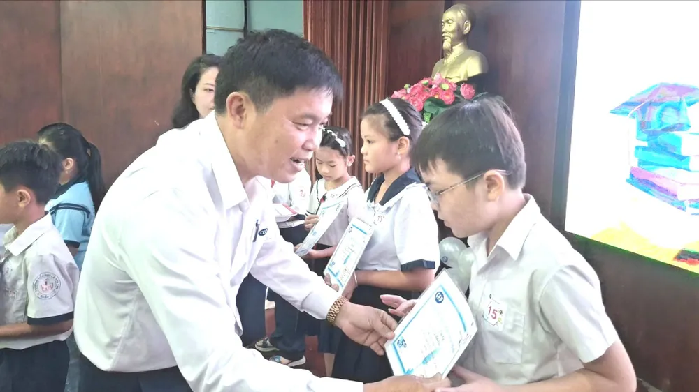 Ông Phan Công Trực, Giám đốc Tổ chức tài chính vi mô CEP, chi nhánh Tân Thới Hiệp, trao học bổng cho con công nhân. Ảnh: HỒNG ĐÀO