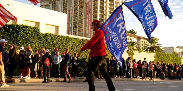Josh Platillero, of Knoxville, Tenn. skates with flags in support of President Trump as people wait for the doors to open outside of the Turning Point USA Student Action Summit, Tuesday, Dec. 22, 2020, in West Palm Beach, Fla. (AP Photo/Lynne Sladky)