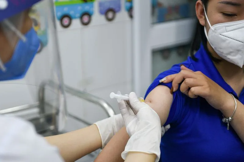 A woman receives a vaccine as Vietnam starts its official rollout of AstraZeneca's COVID-19 vaccine, in Hai Duong