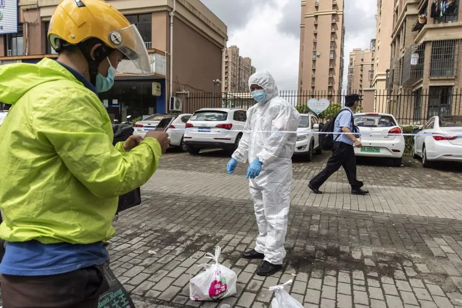 Một nh&acirc;n vi&ecirc;n giao h&agrave;ng đưa h&agrave;ng thiết yếu đến một khu cư d&acirc;n bị phong toả ở Thượng Hải, Trung Quốc h&ocirc;m 3/8 - Ảnh: Bloomberg.