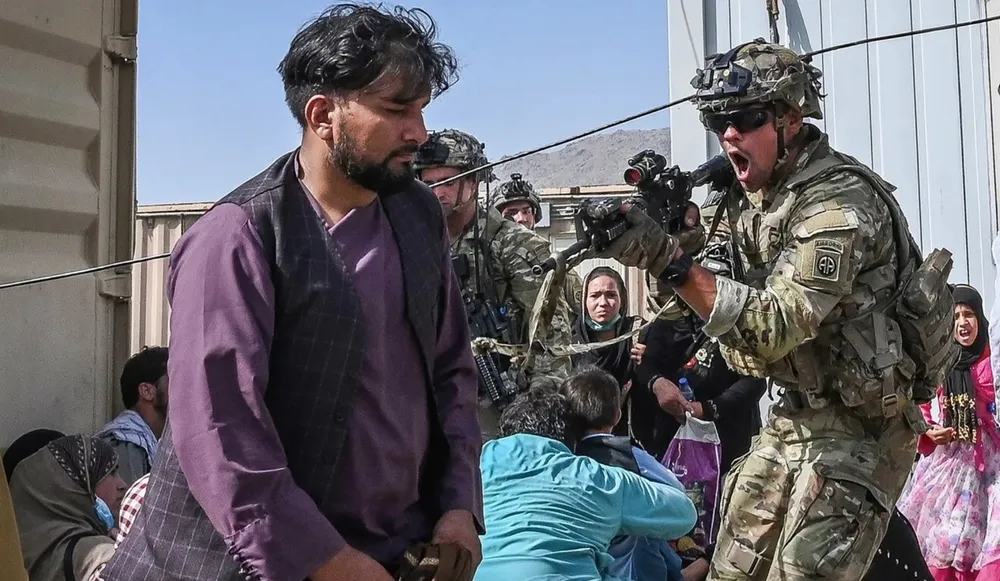  Một binh sĩ Mỹ chĩa súng về phía một người Afghanistan tại sân bay Kabul trong lúc hỗn loạn hôm 16-8. Ảnh: AFP