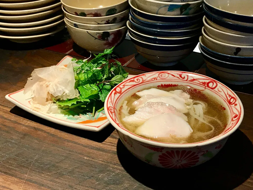 An Com’s pho noodles come in a clear-golden chicken broth and are topped with slices of pure white breast meat, with a wedge of lime and plenty of aromatic herbs on the side. | ROBBIE SWINNERTON 