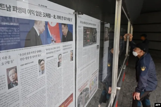 Một người đàn ông đang đọc tờ báo được treo trên phố ở Seoul, ngày 21/10/2024, có ảnh bên trái của nhà lãnh đạo Triều Tiên Kim Jong Un và Tổng thống Nga Vladimir Putin tại một buổi tiệc ở Bình Nhưỡng vào đầu năm nay.