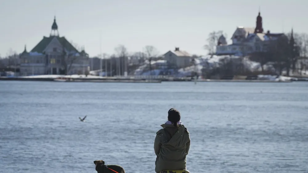 Một người phụ nữ tận hưởng một ngày nắng và lạnh giá trên bờ kè của Cảng Nam ở Helsinki, Phần Lan.