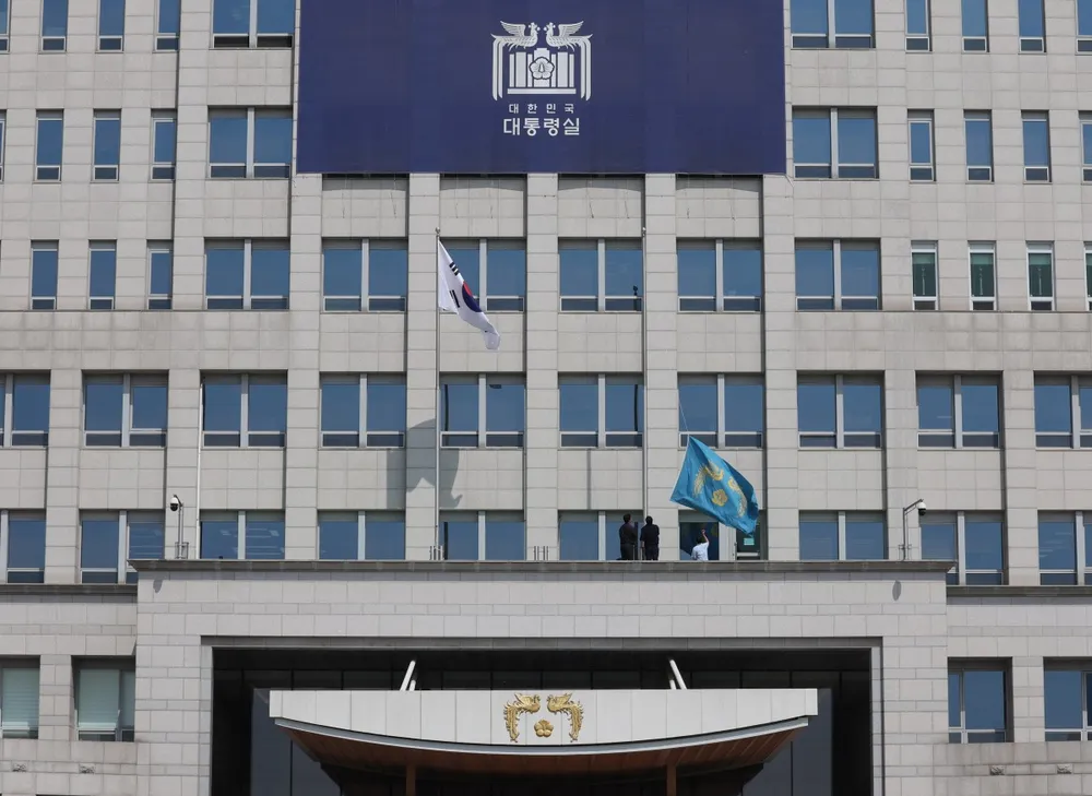 Một lá cờ (phải) mang biểu tượng Tổng thống Hàn Quốc được hạ xuống tại Văn phòng Tổng thống ở Seoul vào ngày 4 tháng 4 năm 2025, sau khi Tòa án Hiến pháp duy trì việc luận tội Tổng thống Yoon Suk Yeol. Ảnh của Yonhap