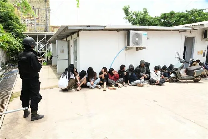 Lực lượng chức năng thuộc Bộ Công an Lào áp giải các đối tượng bị bắt giữ trong vụ triệt phá. Ảnh: TTXVN