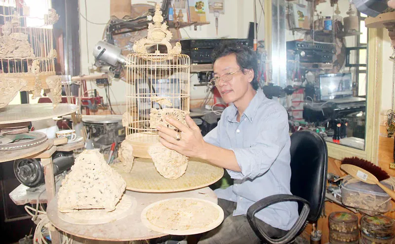 Nghệ nhân Đoàn Minh Căn bên chiếc lồng chim bằng tre tinh xảo