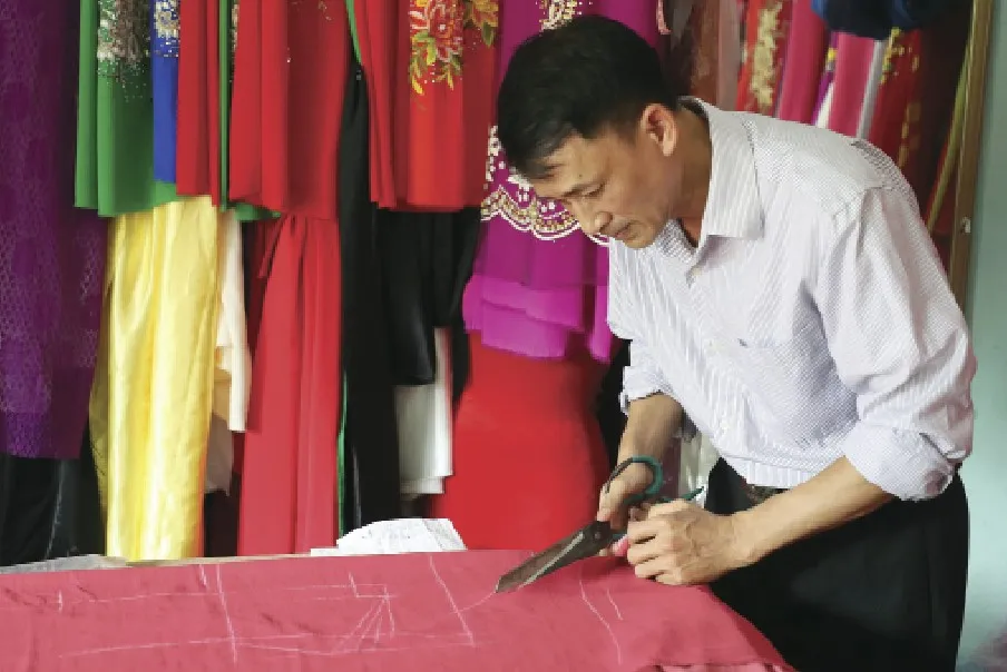 Anh Lê Văn Duẩn cắt vải chuẩn bị may áo dài. Ảnh: QUANG PHÚC