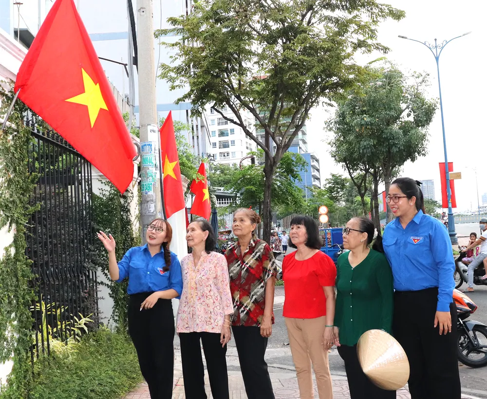 Bà Nguyễn Thị Nhì (thứ 2, từ trái qua) cùng người dân tham quan Đường cờ Tổ quốc trên đường Bến Vân Đồn (quận 4)