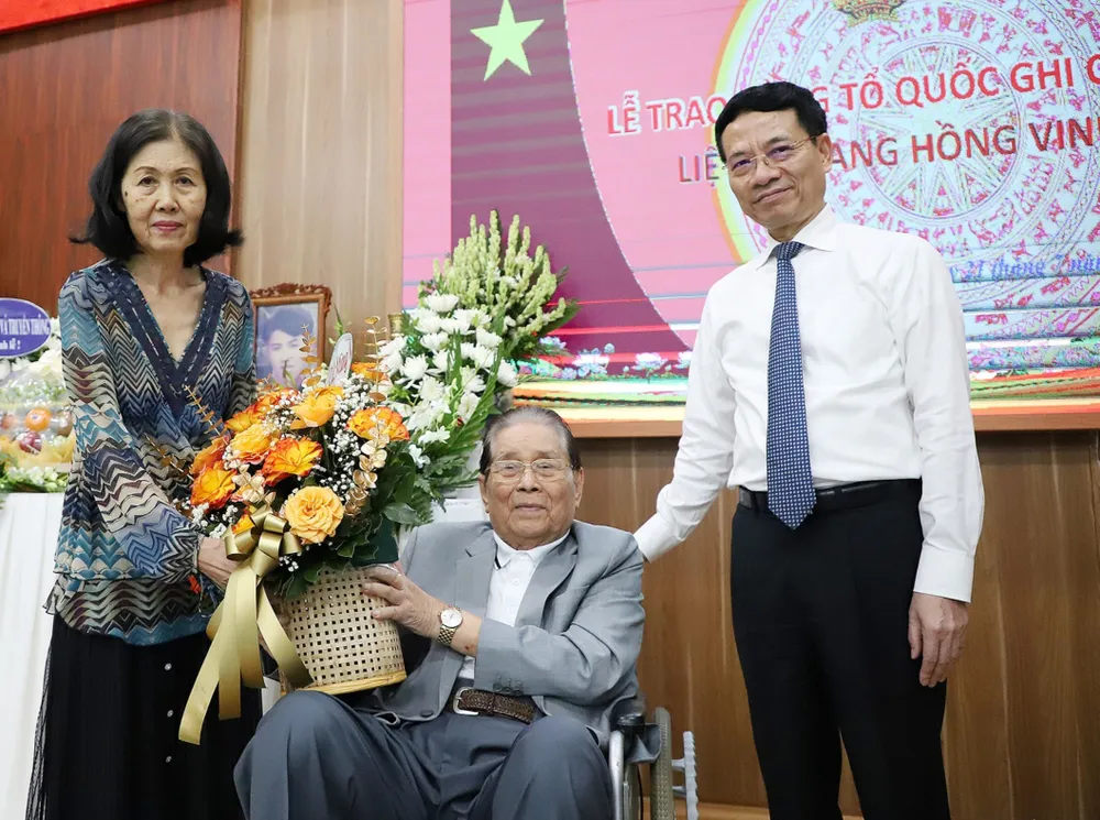 Bộ trưởng Bộ TT-TT Nguyễn Mạnh Hùng và bà Huỳnh Thị Thủy Tiên tặng hoa cảm ơn ông Nguyễn Bá trong ngày trao bằng Tổ quốc ghi công cho liệt sĩ Trang Hồng Vinh