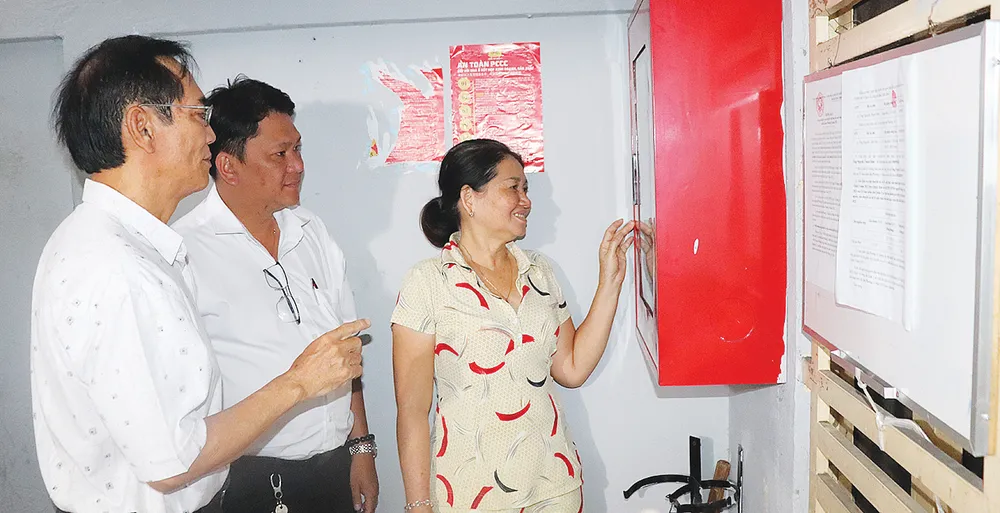 Ông Nguyễn Văn Quang (bìa trái), Bí thư chi bộ khu phố 4, phường 14, quận 5 hướng dẫn người dân chung cư sử dụng tủ phòng cháy chữa cháy
