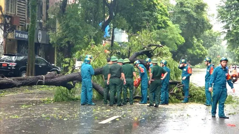 Lực lượng quân đội và dân quân tự vệ thu dọn cây đổ trên phố Bà Triệu. Ảnh: QUỐC KHÁNH