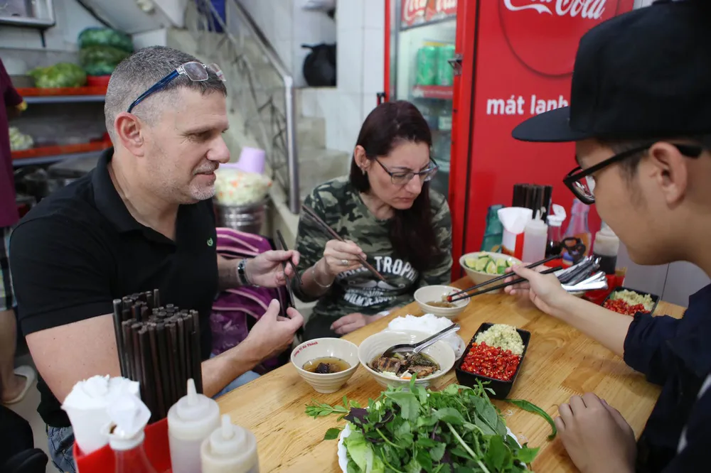 Du khách nước ngoài thưởng thức bún chả Việt Nam. Ảnh: HOÀNG TRIỀU
