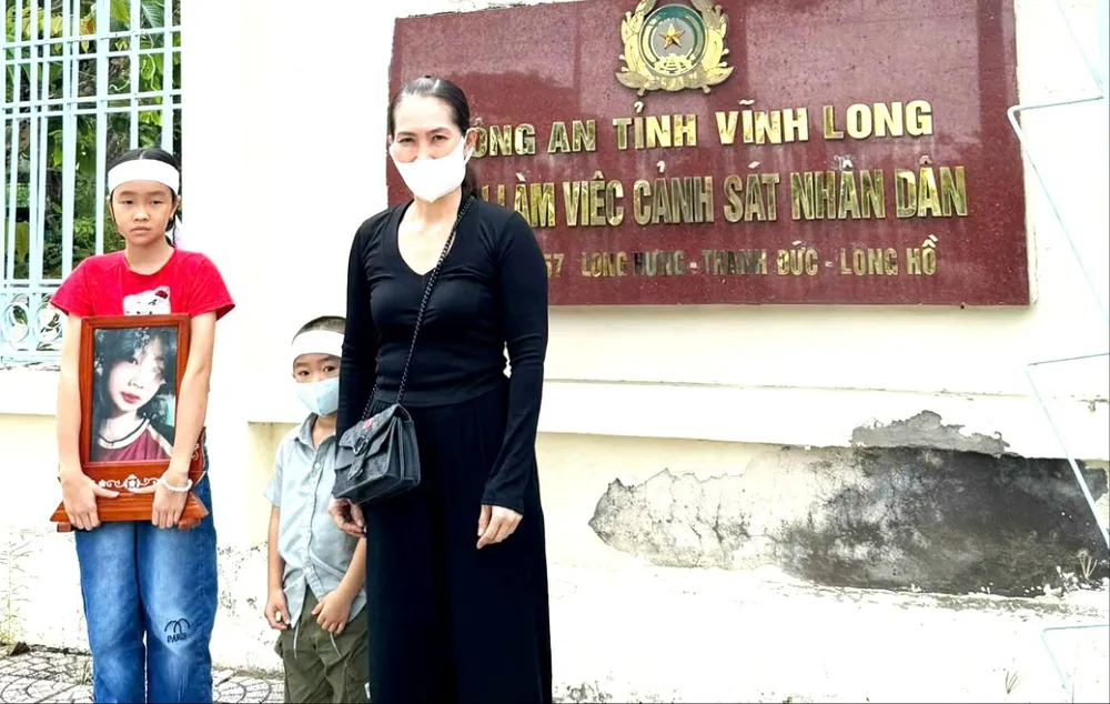 Bà Hiền cùng 2 con nhỏ và di ảnh bé Bảo Tr., trước Công an tỉnh Vĩnh Long