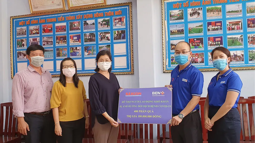 Đại diện Công đoàn BIDV trao tượng trưng cho đại diện Ban Biên tập Báo SGGP 400 phần quà giúp người nghèo vượt khó. Ảnh: LÊ NHUNG