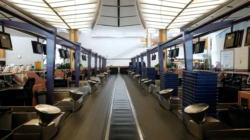 Một băng chuyền hành lý chạy giữa các hàng của quầy làm thủ tục trống tại sân bay Changi ở Singapore. Nguồn: Reuters
