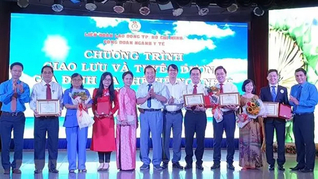 Lãnh đạo Liên đoàn Lao động TPHCM cùng Công đoàn ngành y tế TP trao biểu trưng tuyên dương gia đình ba thế hệ ngành y năm 2020. Ảnh: THANH VŨ/TTXVN