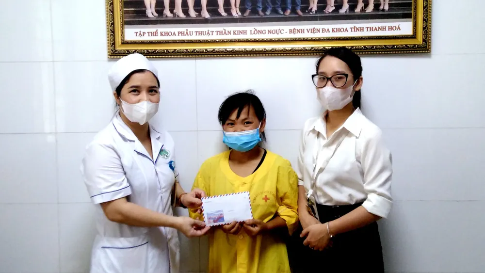 Thay mặt Báo SGGP, đại diện Phòng Công tác xã hội và Khoa Phẫu thuật thần kinh - Lồng ngực (Bệnh viện Đa khoa tỉnh Thanh Hóa) trao tiền hỗ trợ cho chị Hoàng Thị Thương - vợ anh Nguyễn Văn Hưởng