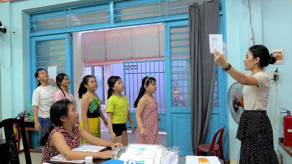 Chị Nguyễn Thị Tuyết Như luyện từ vựng tiếng Anh thông qua trò chơi cho các em tại nhà sinh hoạt cộng đồng (Khu dân cư Trung Bình A3, phường Thạc Gián, quận Thanh Khê, TP Đà Nẵng)