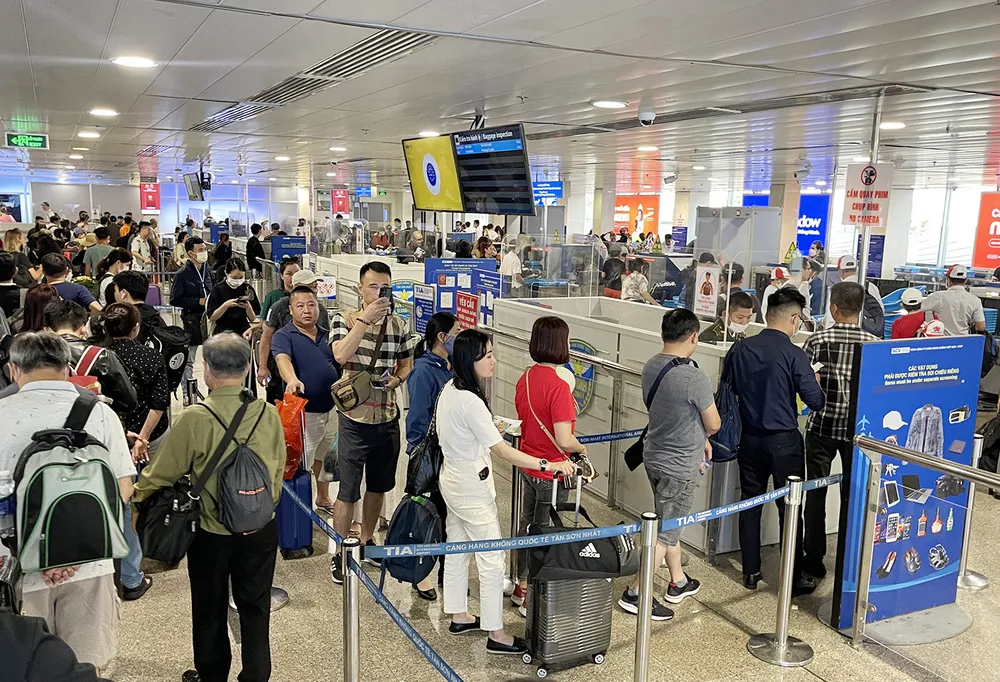 Hành khách xếp hàng làm thủ tục lên máy bay tại Cảng hàng không Tân Sơn Nhất. Ảnh: HOÀNG HÙNG