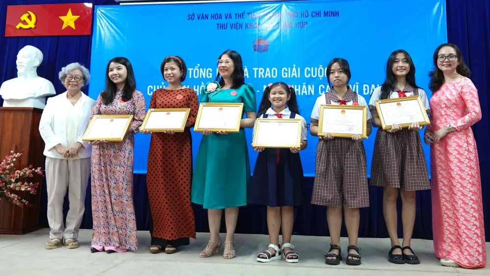 Phó Giám đốc Thư viện KHTH TPHCM Nguyễn Thị Mai Thy và nhà văn Kim Hài trao giải nhất cho 6 thí sinh có bài viết hay, tranh vẽ đẹp tham gia cuộc thi "Chủ tịch Hồ Chí Minh - Một nhân cách vĩ đại". Ảnh: THÚY BÌNH