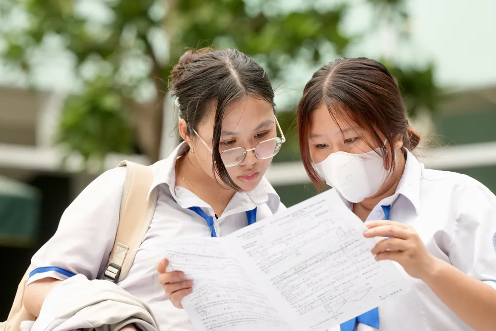  Thí sinh trao đổi đề thi Toán sau khi rời phòng thi, tại điểm thi Trường THCS Colette, quận 3, chiều 27-6. Ảnh: HOÀNG HÙNG