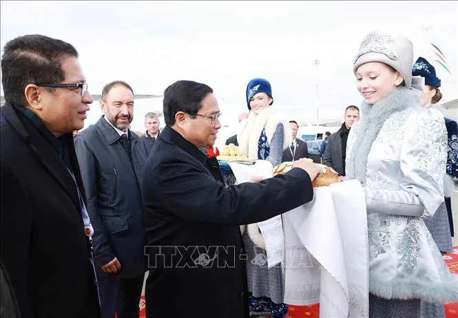 Thiếu nữ Nga trong trang phục truyền thống trân trọng mời Thủ tướng Phạm Minh Chính thưởng thức bánh mì chấm muối theo nghi thức đón khách quý của Nga. Ảnh: TTXVN