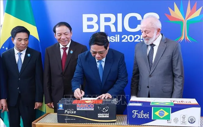 Thủ tướng Phạm Minh Chính ký vào thùng hàng tượng trưng sản phẩm cá tra, ba sa và cá rô phi của Việt Nam xuất sang Brazil. Ảnh: TTXVN