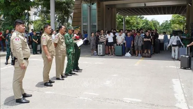 Lực lượng chức năng Việt Nam và Campuchia làm thủ tục bàn giao, tiếp nhận công dân được trao trả. Ảnh: TTXVN
