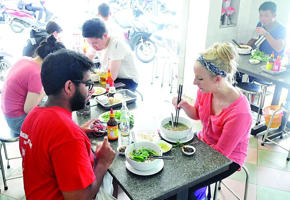Du khách ăn phở bên đường Phạm Ngũ Lão Ảnh: THÀNH TRÍ