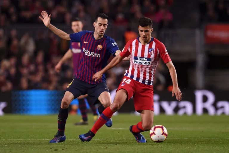 Rodri đi bóng trước Sergio Busquets của Barcelona.