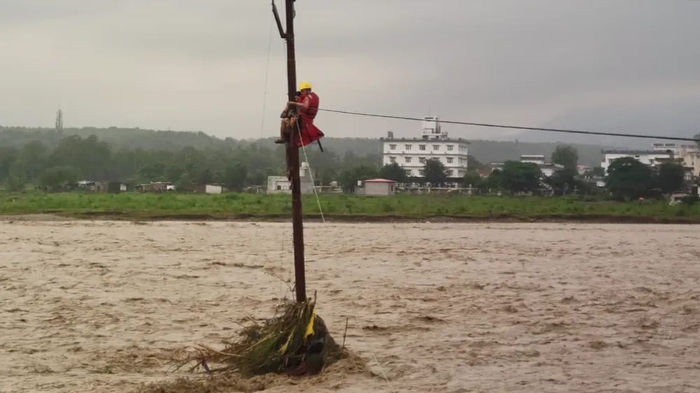 Nhân viên cứu hộ giải cứu một thiếu niên trèo lên cây và dùng dây điện để cứu mình khỏi trận lũ lụt ở Uttarakhand. Ảnh : NDRF