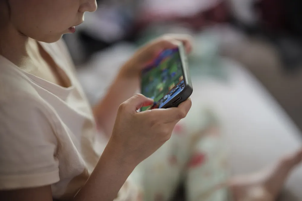 Child_uses_smartphone_to_play_games_at_home_closeup.jpg