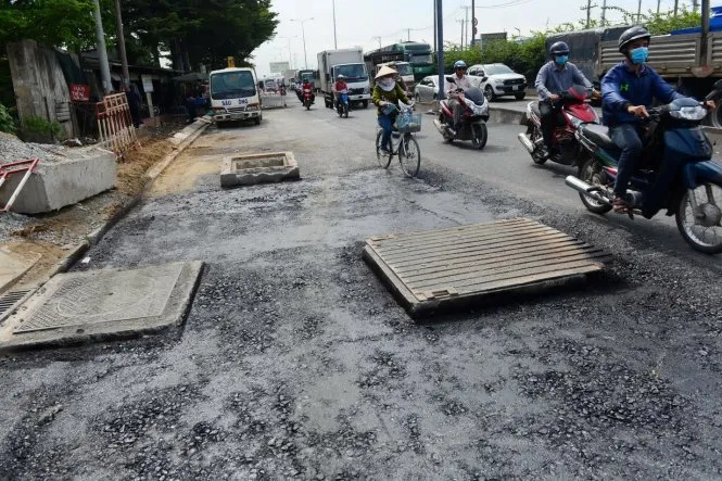 Nắp cống lồi hơn mặt đường cả gang tay buộc xe máy phải lấn sang phần đường dành cho ôtô. Ảnh chụp tại quốc lộ 1A đoạn qua chân cầu Bình Phước 2 - Ảnh: QUANG ĐỊNH