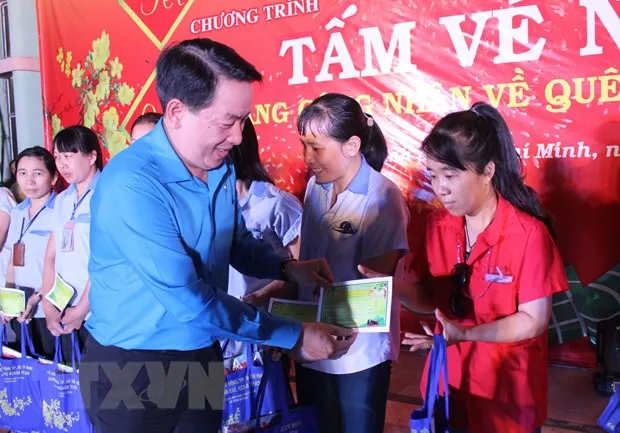 Ông Kiều Ngọc Vũ, Phó Chủ tịch Liên đoàn Lao động Thành phố Hồ Chí Minh trao vé xe về quê ăn Tết cho công nhân. (Ảnh: Xuân Anh/TTXVN)