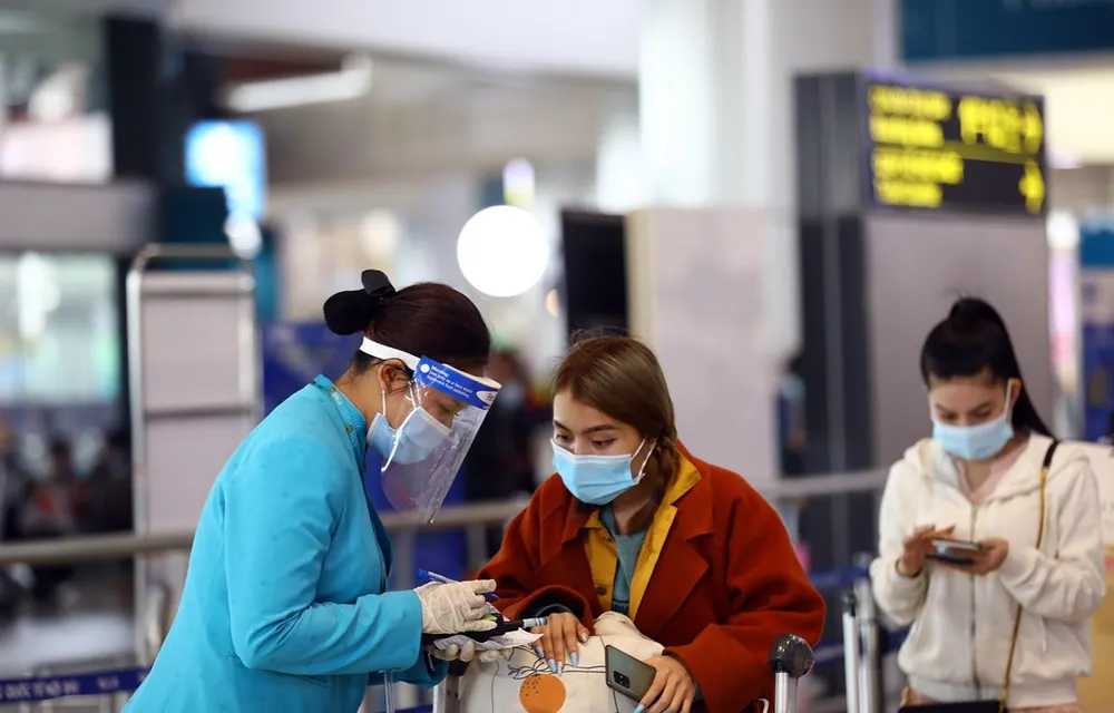 Nhân viên Vietnam Airlines hướng dẫn hành khách đảm bảo phòng chống dịch Covid-19. (Ảnh: Huy Hùng/TTXVN)